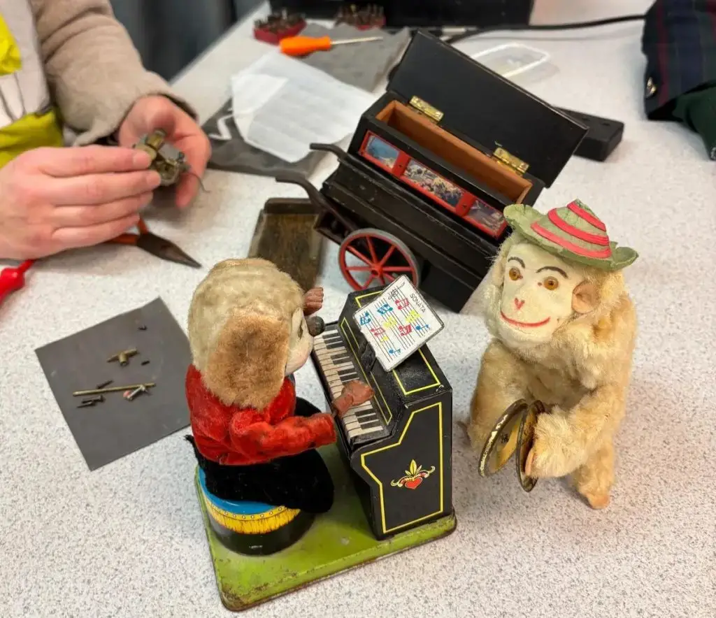Three vintage clockwork toys being repaired